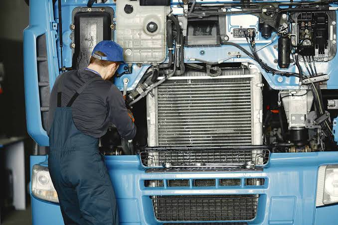 Mechanics diagnosing a semi truck radiator and cooling system in a truck yard